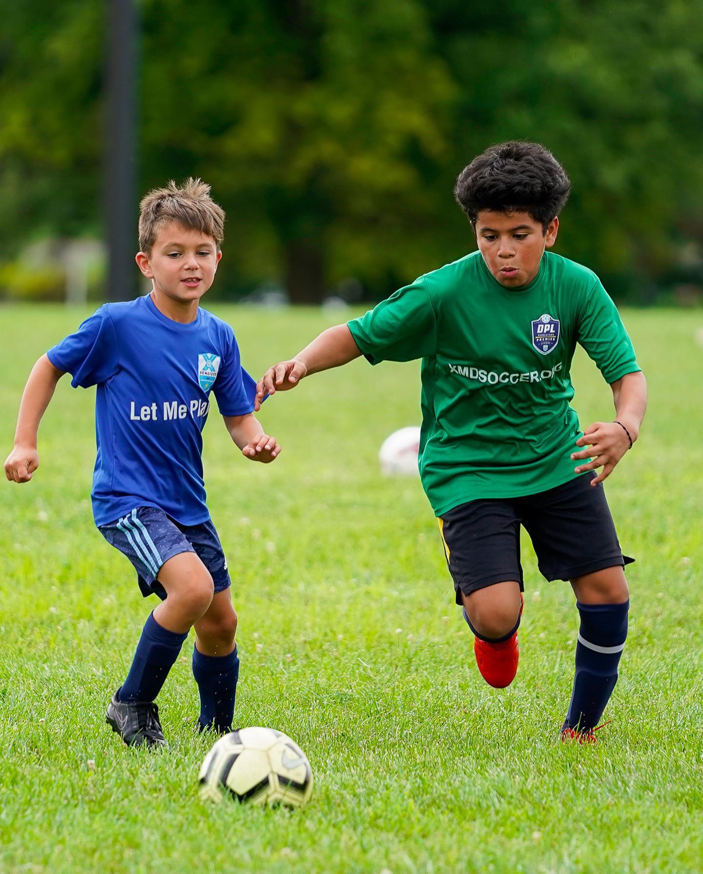 Two young XMD Soccer Academy players competing for the ball in a small-sided league game
